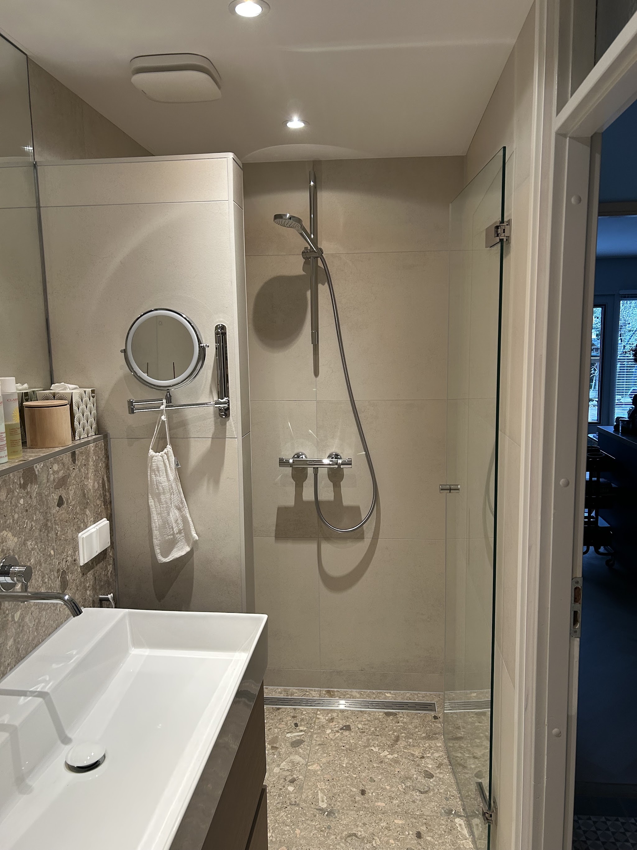 Badkamer met inloopdouche, wit badmeubel en terrazzo-look vloer