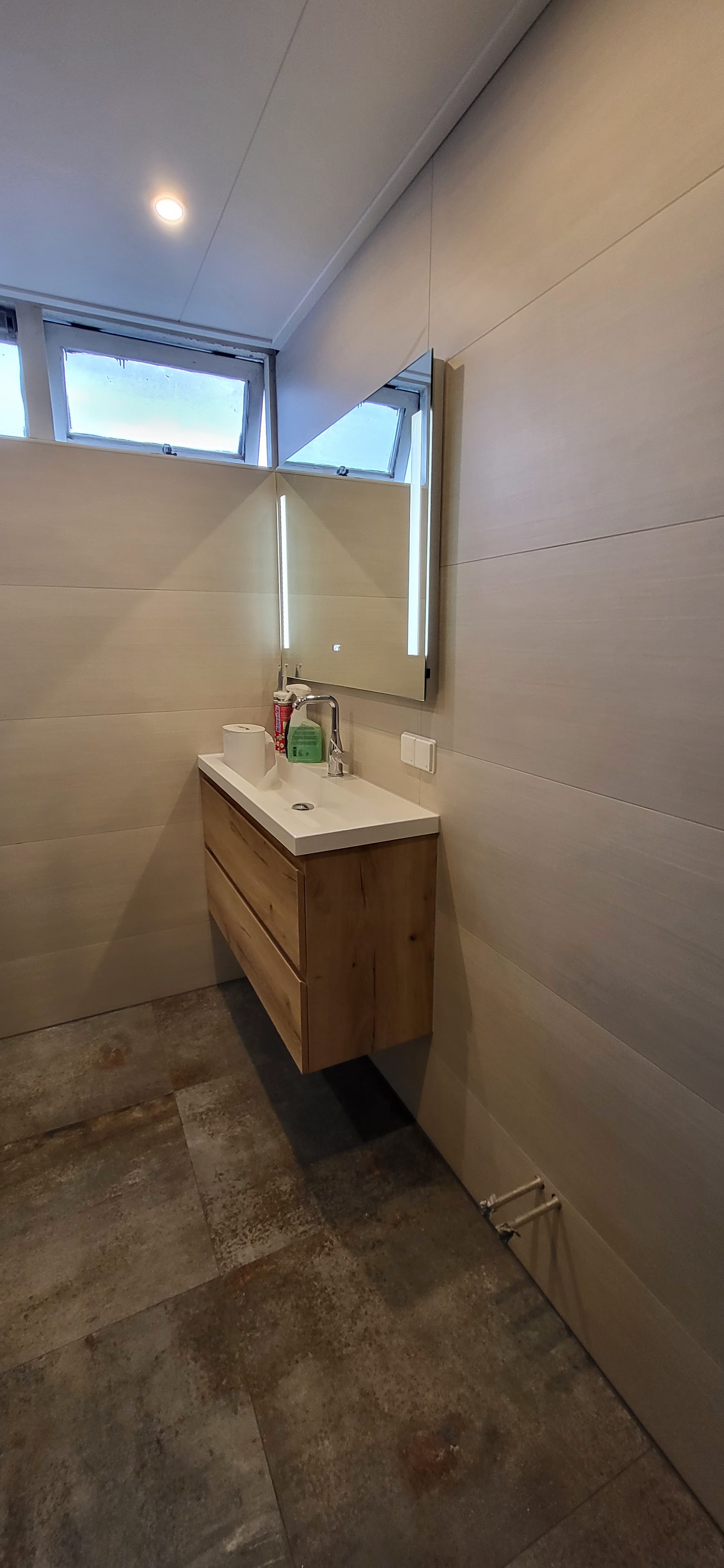Badkamer met zwevend eiken badmeubel en grote wandtegels